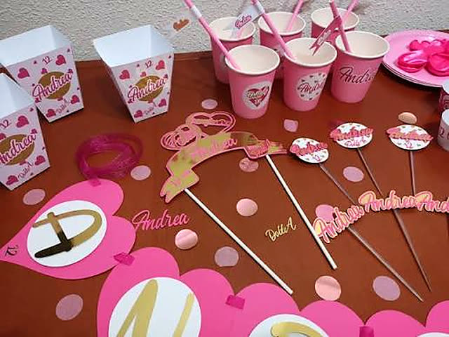 Mesa rosa con vasos, cajitas y toppers personalizados